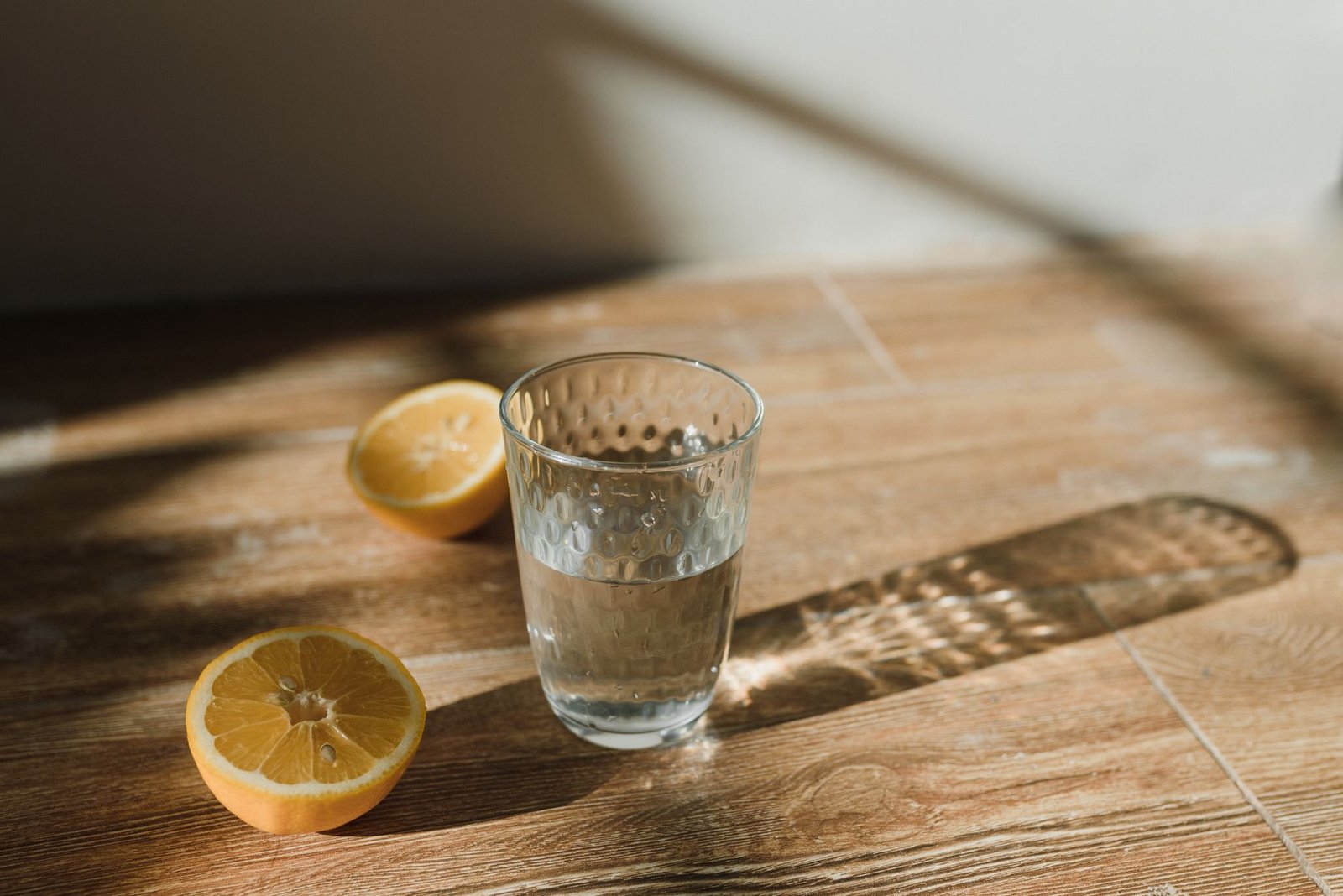 Bicchiere di acqua e limone su un tavolo di legno: come sgonfiarsi in inverno partendo dal mattino