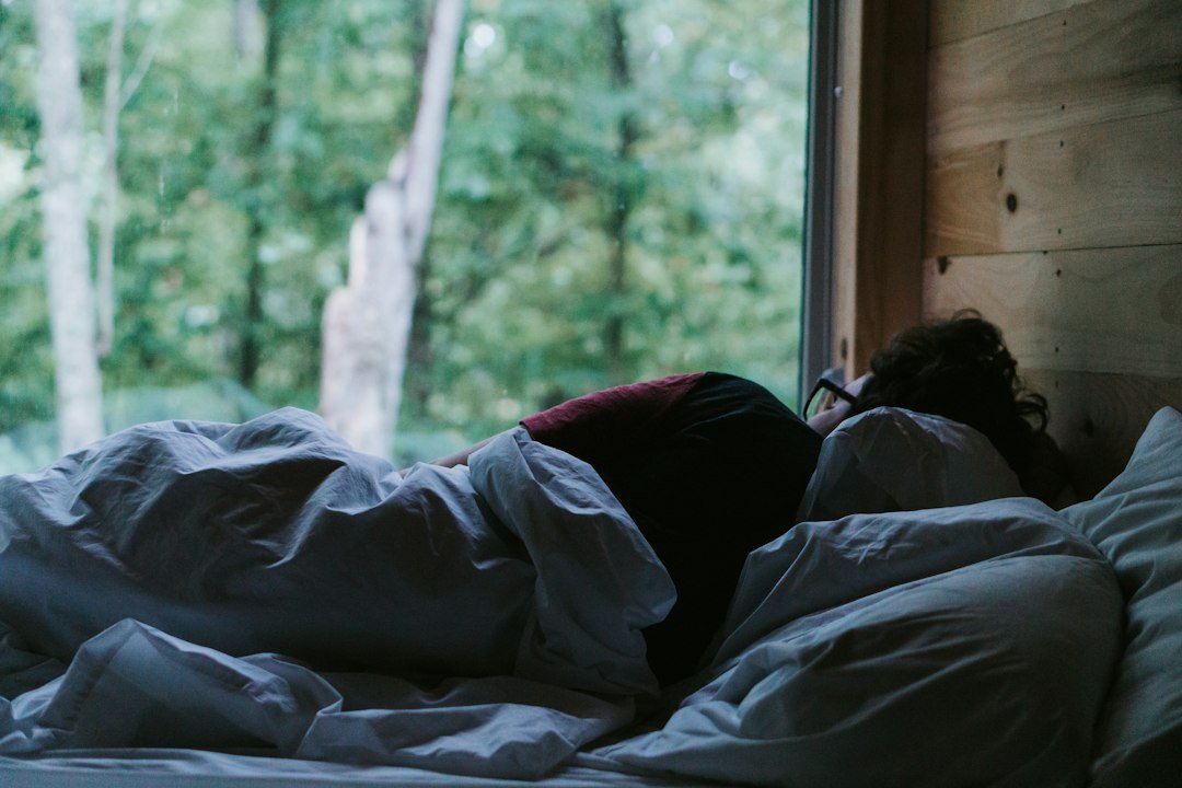 Persona sdraiata a letto sotto una coperta: routine serale per dormire meglio