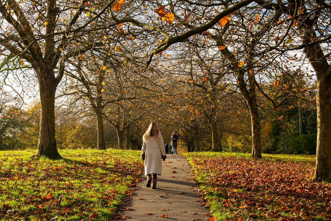 Donna che cammina in un parco tra le foglie d'autunno per combattere la stanchezza autunnale