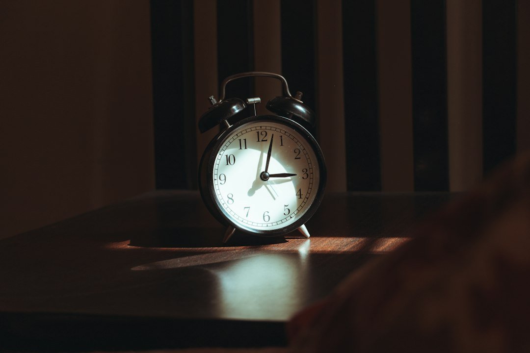 Sveglia su un tavolo di legno di notte: il cambio ora solare e il ritmo del sonno